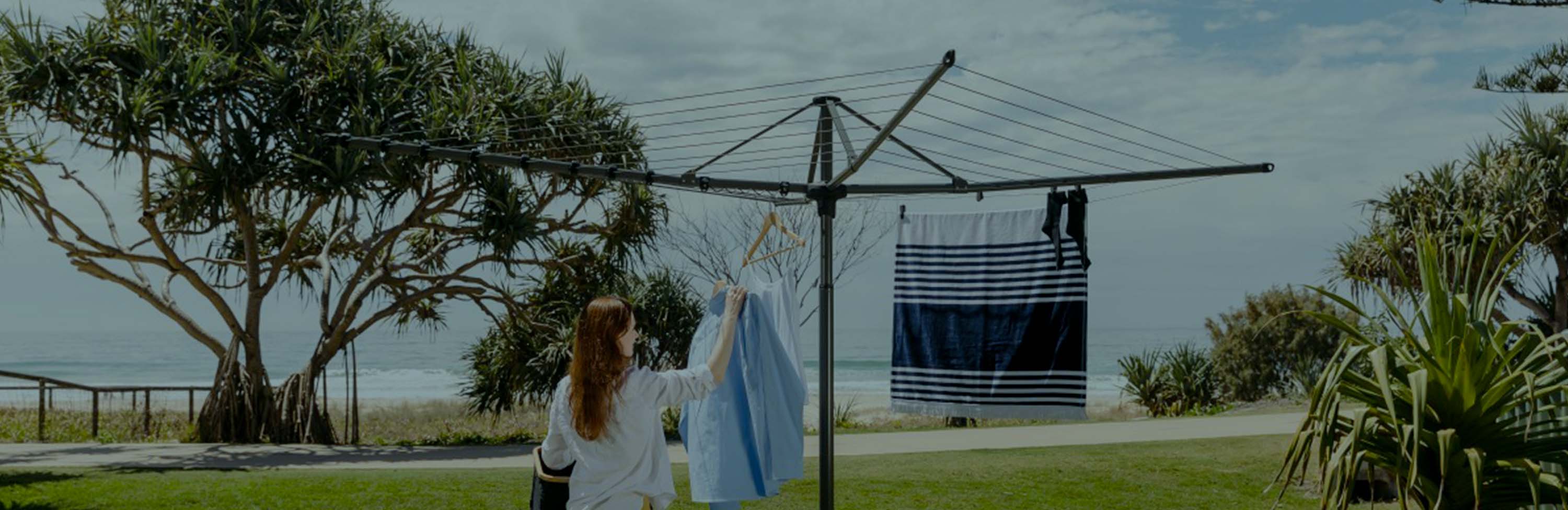 Removable and folding rotary clothesline with woman hanging laundry on the line.