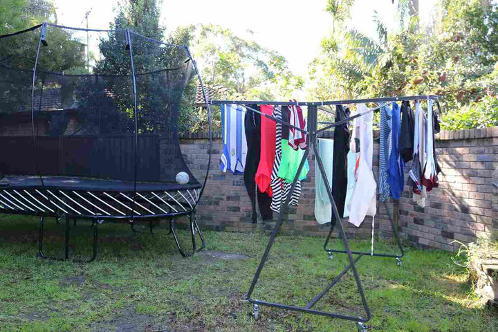 sunchaser mobile clothesline on lawn area by trampoline with washing drying