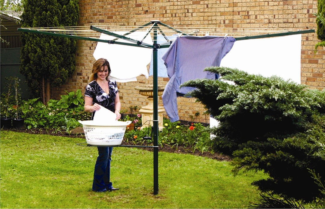 Austral Foldaway 51 Rotary Clothesline cottage green colour and installed in grass area with lady hanging out washing.